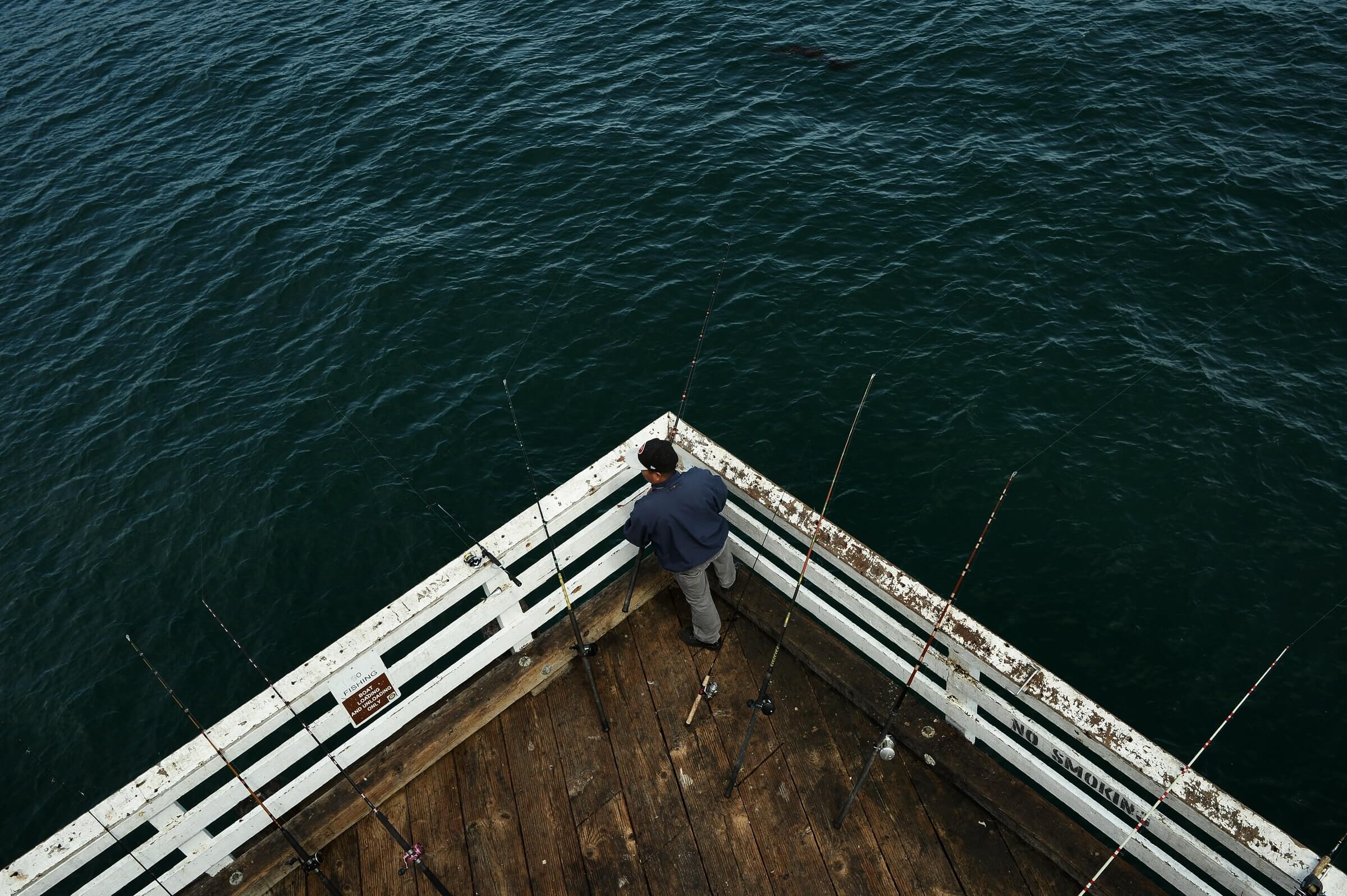 pêcheur avec ses cannes à pêche sur un pont